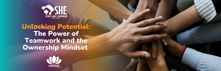 A panoramic banner image visually representing collaboration and synergy. In the center, multiple hands of diverse individuals are stacked on top of each other, signifying teamwork and unity. The background features a soft, blurred gradient transitioning from teal green on the left to vibrant orange and yellow tones on the right. Prominent white and orange text overlays the image, stating "Unlocking Potential: The Power of Teamwork and the Ownership Mindset." The "SHE: Secure, Hope, Empowered" logo is in the top left corner, and the "catalyst foundation" lotus logo is in the bottom center.